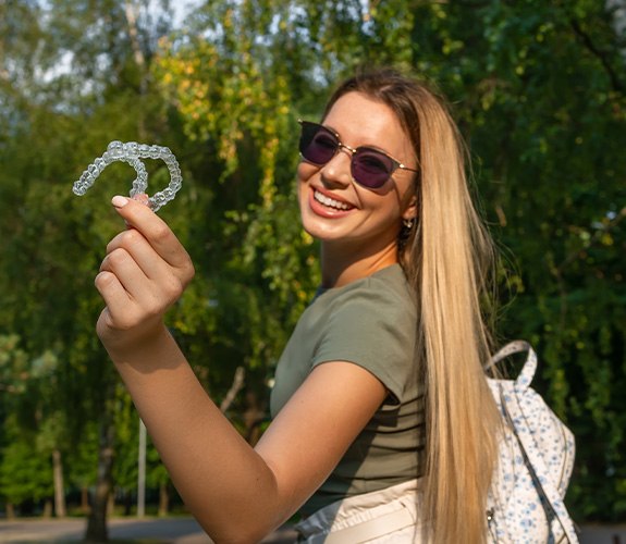 Hand holding two Clear Aligners against blue background