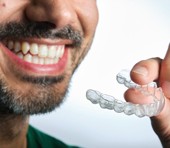 Man holding clear aligner in Aurora