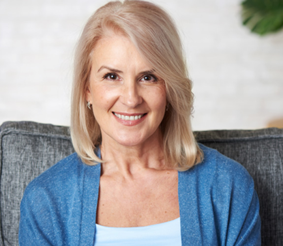 Older woman smiling after discovering how dentures are made in Aurora