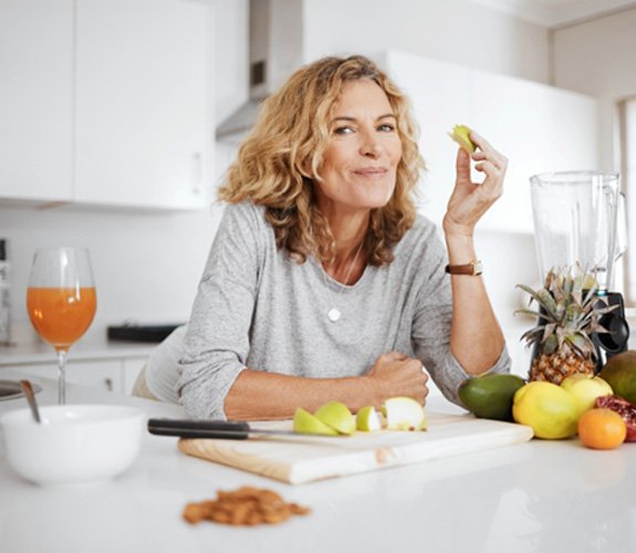 Woman eating an apple in the kitchen 