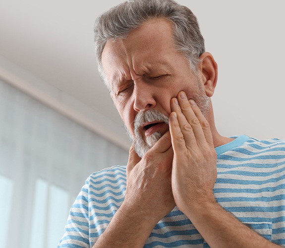 man holding cheek and jaw in pain
