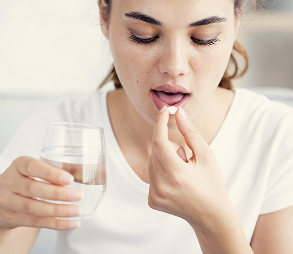 woman taking pill and holding water