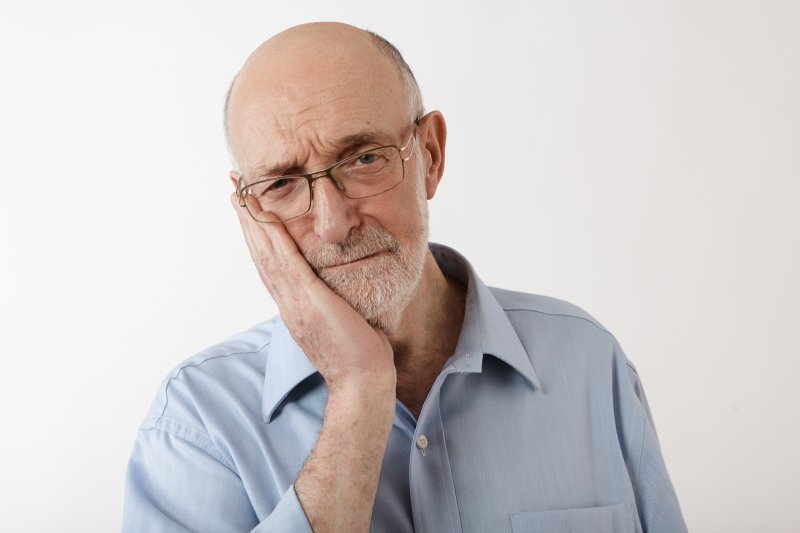 older man holding cheek and experiencing pain